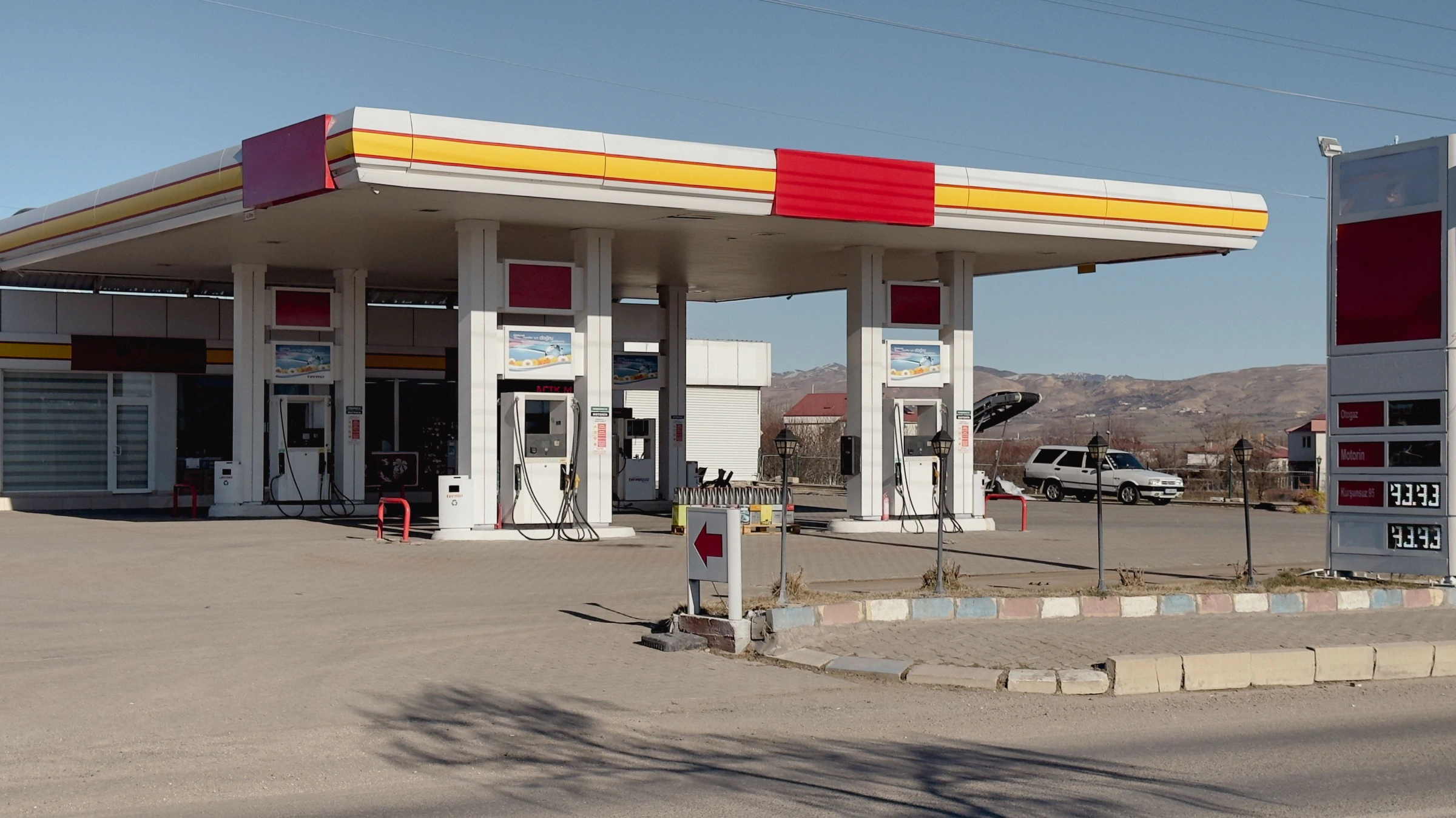 A fuel station forecourt under a lit canopy