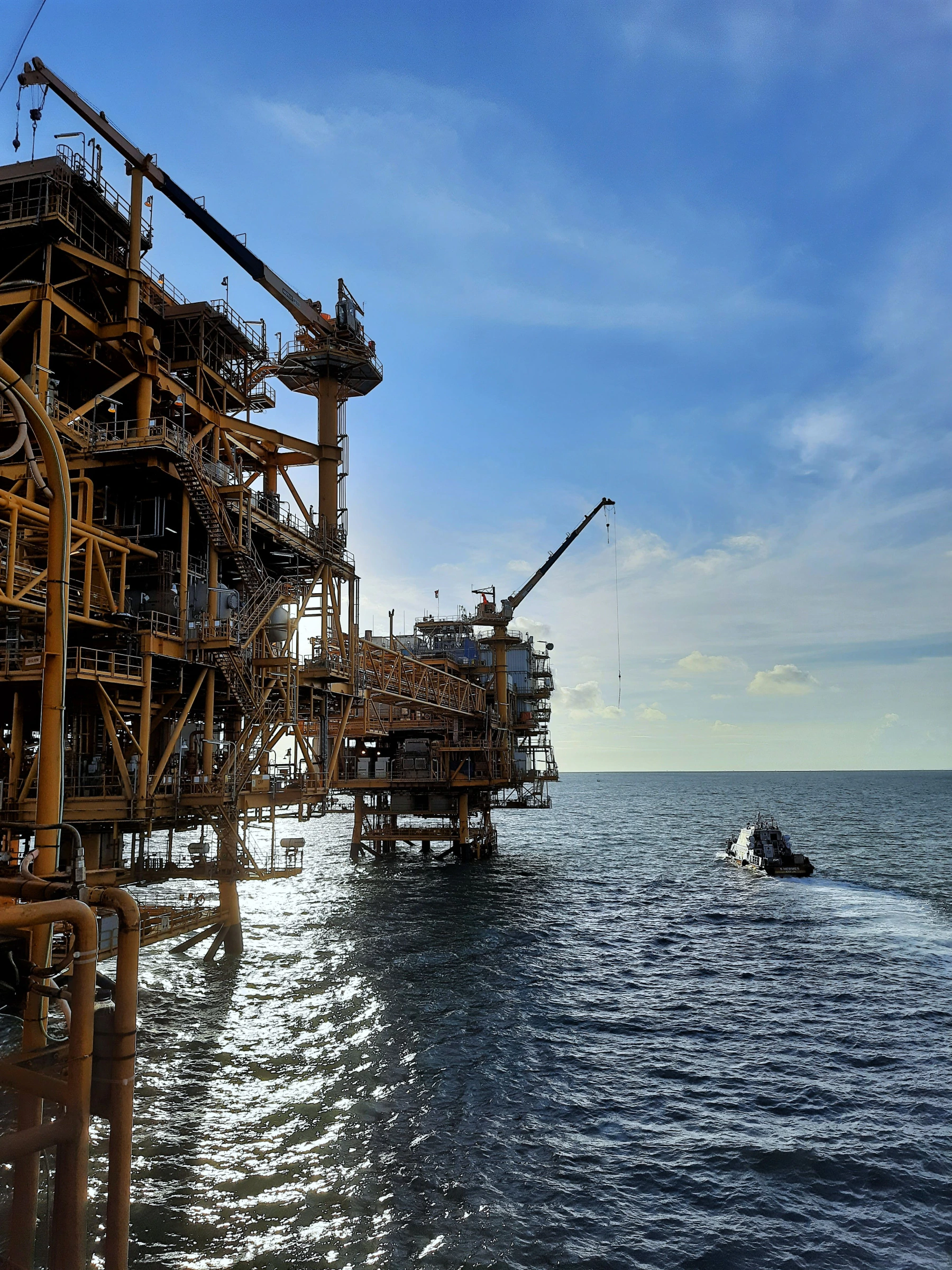 An offshore production platform with a supply vessel approaching