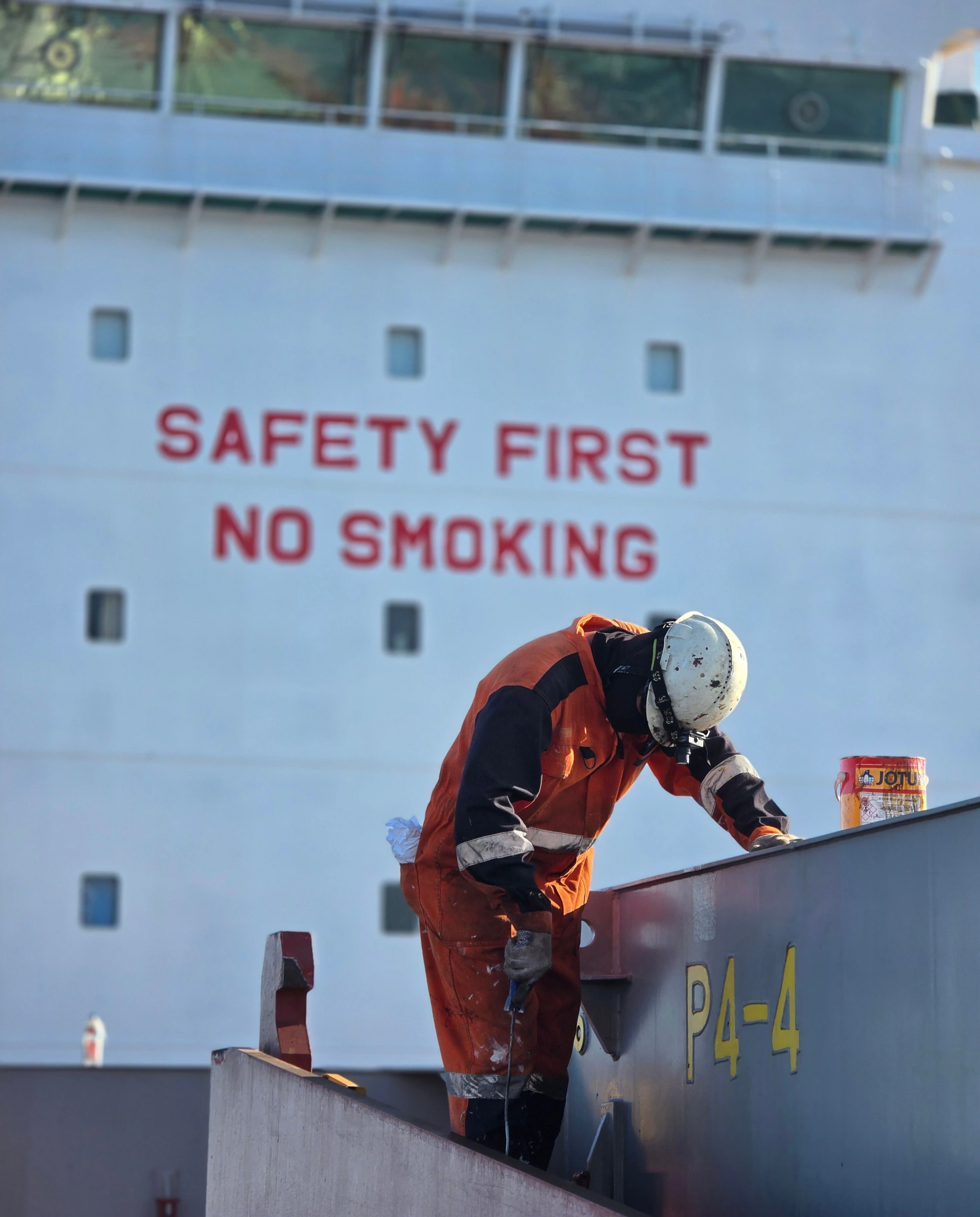 A crew member working on deck below painted safety signage